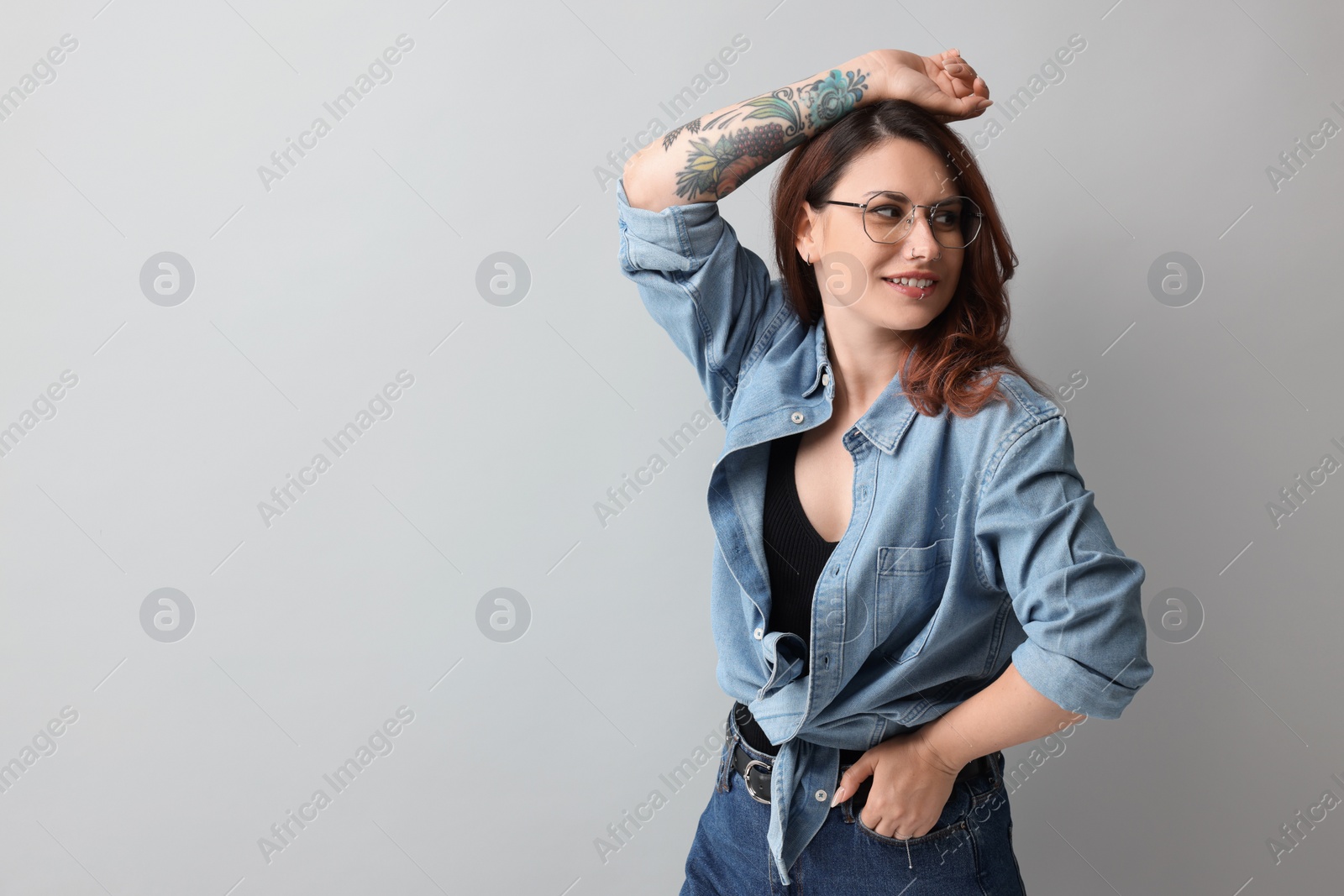 Photo of Beautiful tattooed woman on gray background, space for text