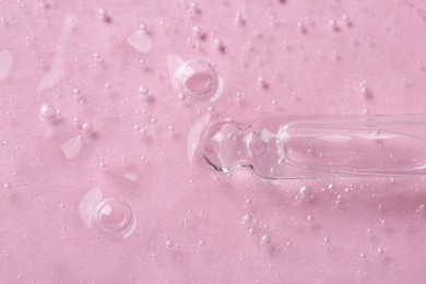 Pipette with cosmetic serum on pink background, top view. Space for text