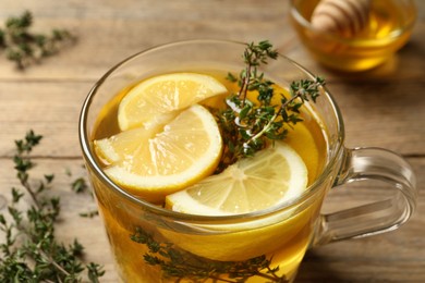 Photo of Fresh thyme tea with pieces of lemon on table, closeup