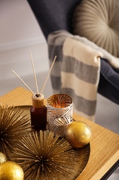 Elegant Christmas decor and reed diffuser on table indoors. Interior design