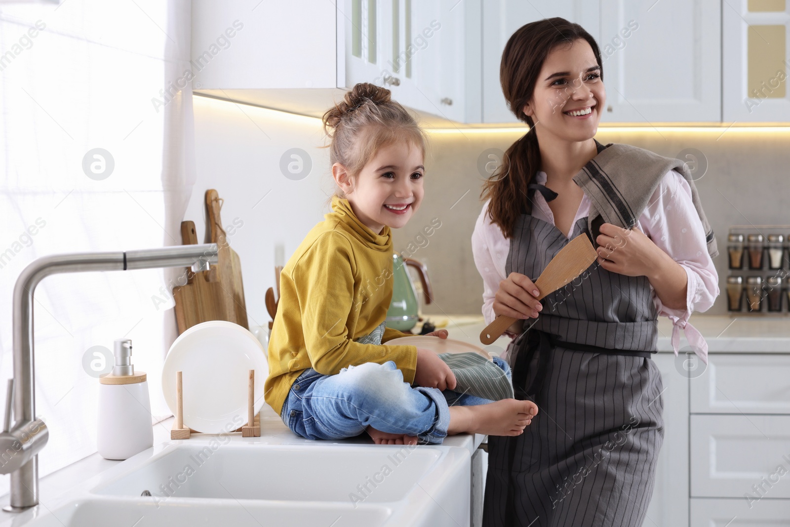 Photo of Young mother and her daughter spending time together in kitchen