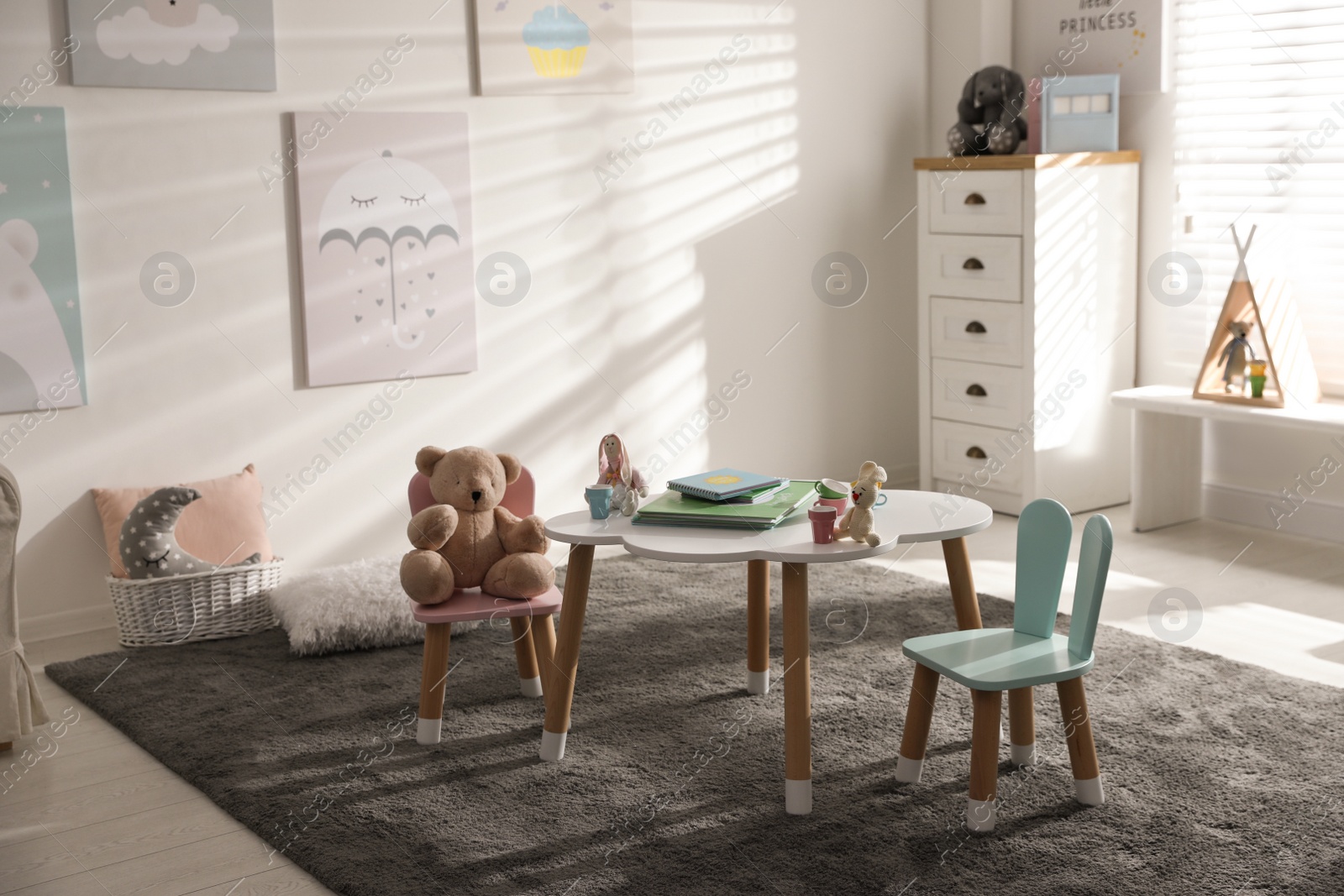 Photo of Small table and chairs with bunny ears in children's room interior