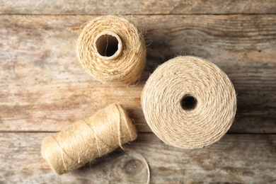 Natural hemp rope spools on wooden background, flat lay