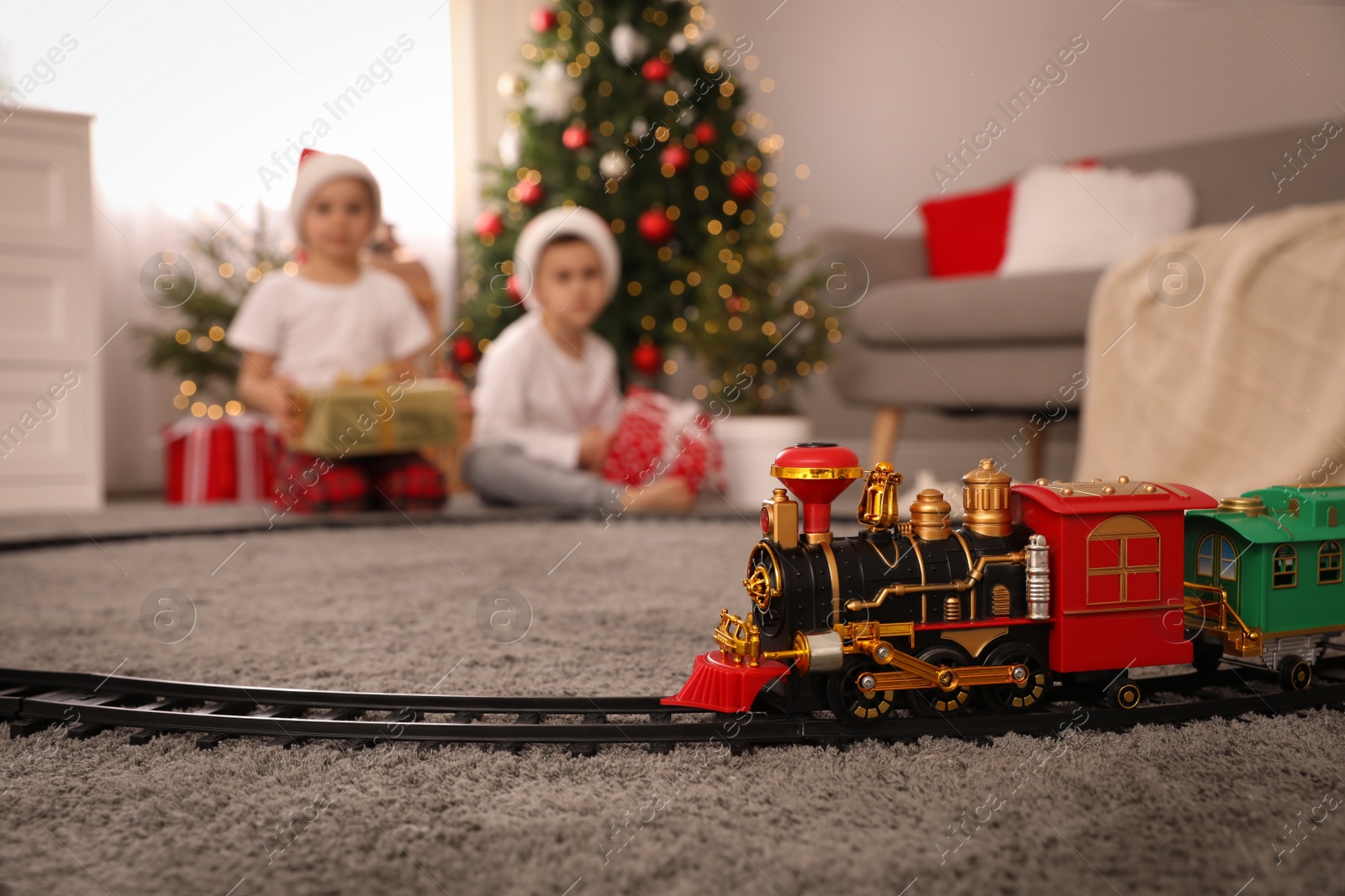 Photo of Children playing with colorful toy in room decorated for Christmas, focus on train