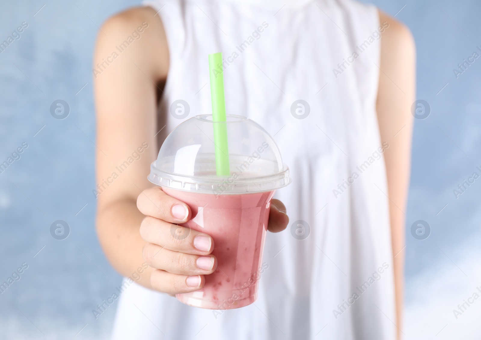 Photo of Woman with tasty milk shake on blue background, closeup