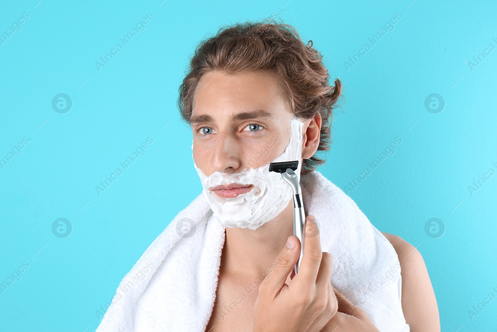 Photo of Handsome young man shaving on color background