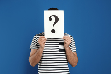 Photo of Man holding question mark sign on blue background