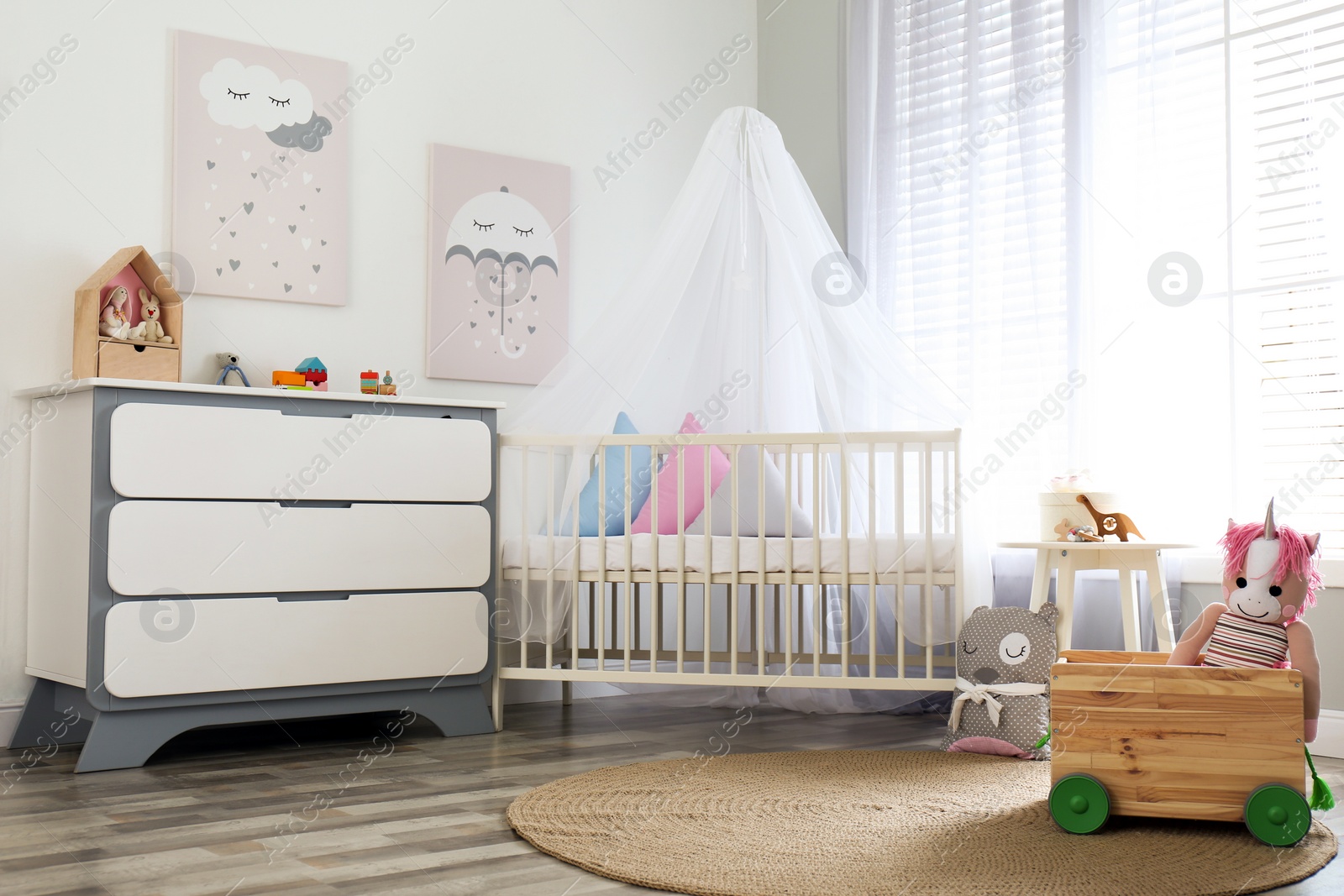 Photo of Baby room interior with cute posters, chest of drawers and comfortable crib