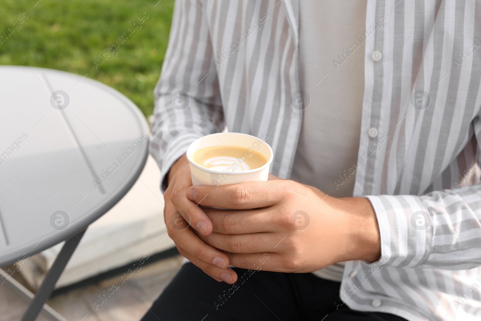 Photo of Coffee to go. Man with paper cup of drink outdoors, closeup