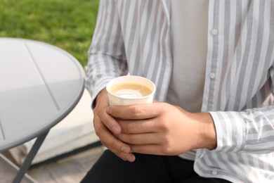 Coffee to go. Man with paper cup of drink outdoors, closeup