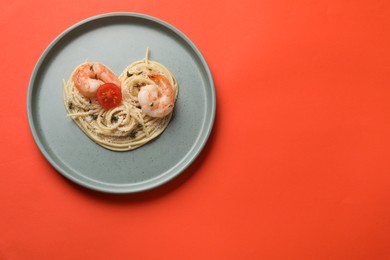 Photo of Heart made of tasty spaghetti, tomato, shrimps and cheese on coral background, top view. Space for text