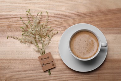 Aromatic coffee, flowers and Good Morning! message on wooden table, flat lay