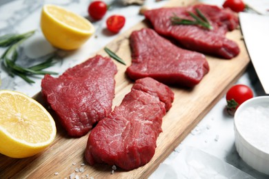 Fresh raw meat steaks and spices on white marble table, closeup