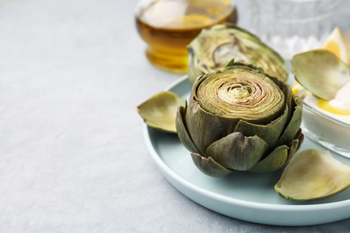 Delicious cooked artichokes with tasty sauce on grey table, closeup. Space for text