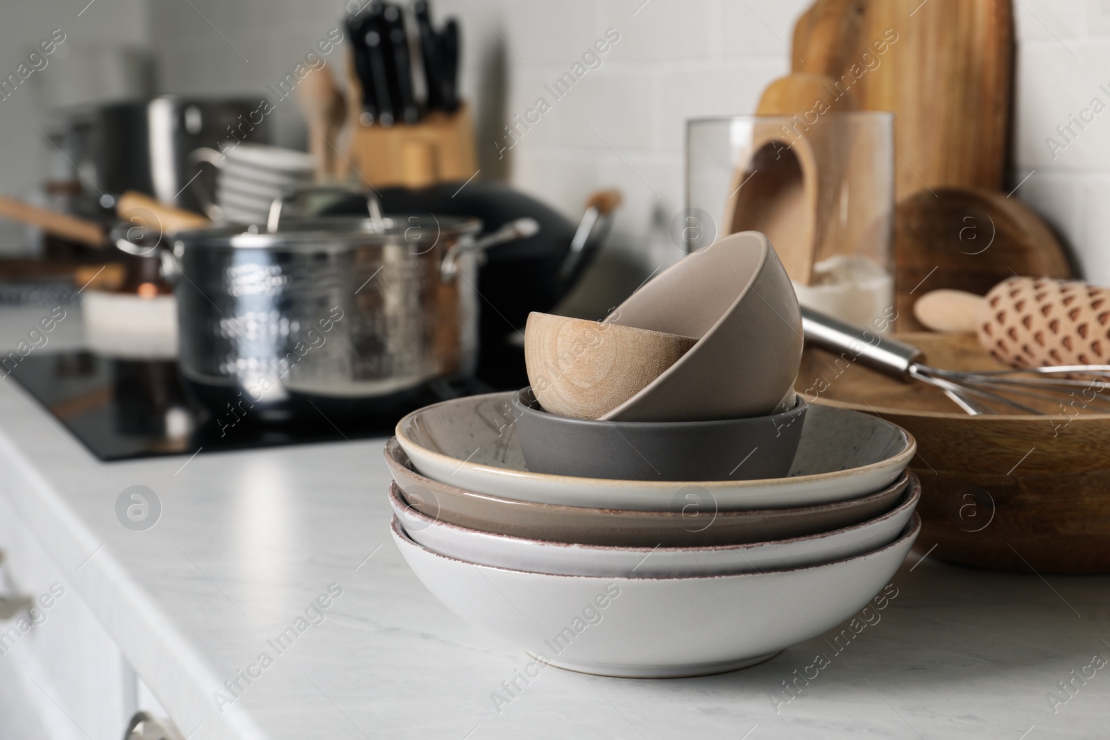 Photo of Stack of bowls and different cooking utensils on countertop in kitchen, space for text