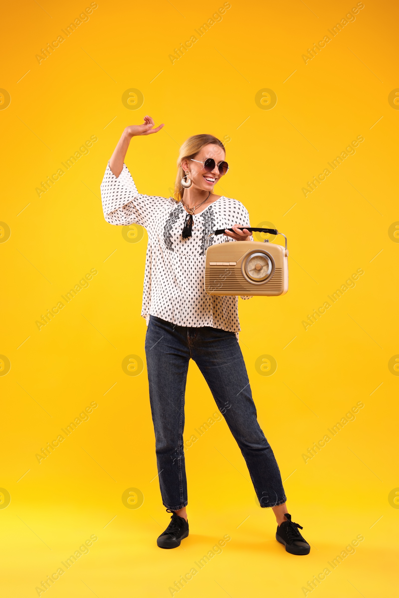 Photo of Portrait of happy hippie woman with retro radio receiver on yellow background