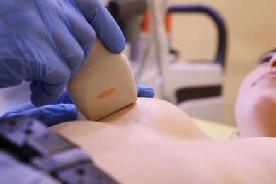 Photo of Mammologist conducting ultrasound examination of woman's breast in clinic, closeup