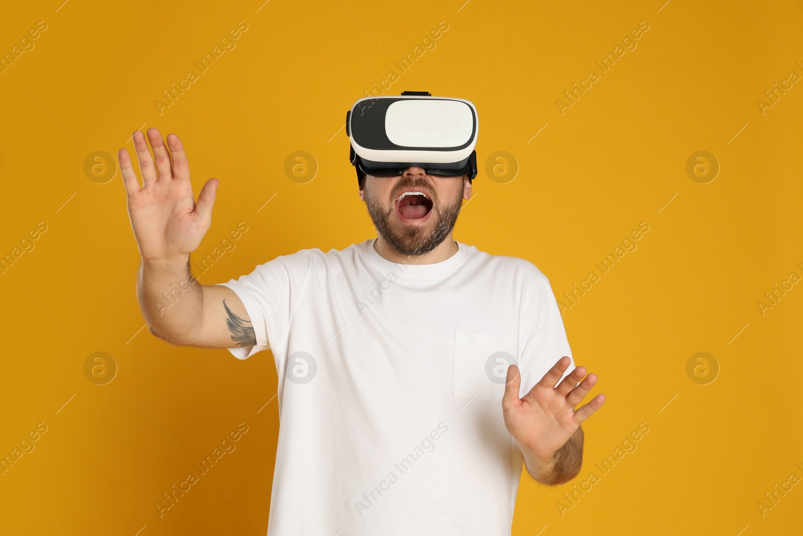 Photo of Emotional man using virtual reality headset on yellow background