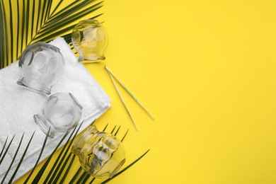 Photo of Glass cups, tweezers, towel and leaves on yellow background, flat lay with space for text. Cupping therapy