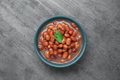 Photo of Bowl of canned kidney beans with parsley on grey table, top view