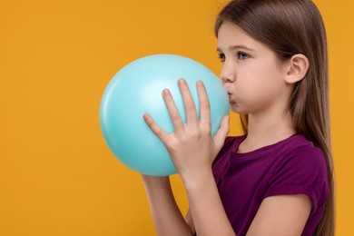 Girl inflating bright balloon on orange background, space for text