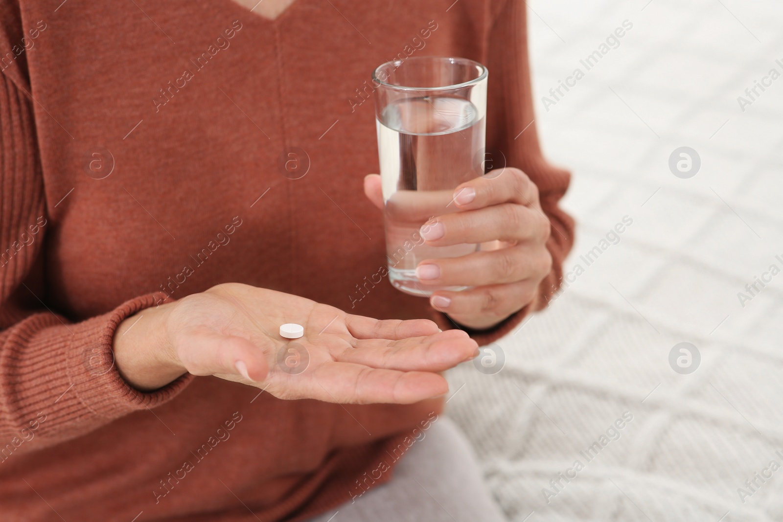Photo of Senior woman with pill and glass of water indoors, closeup