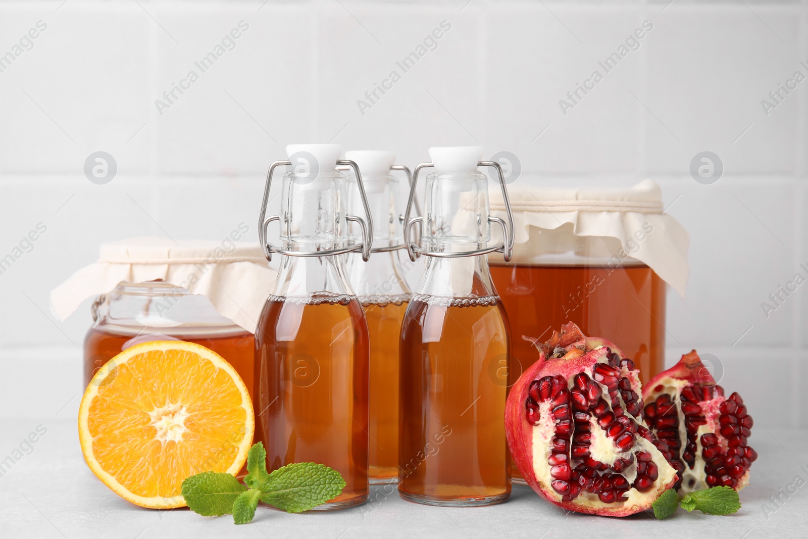 Photo of Tasty kombucha, fresh fruits and mint on white table