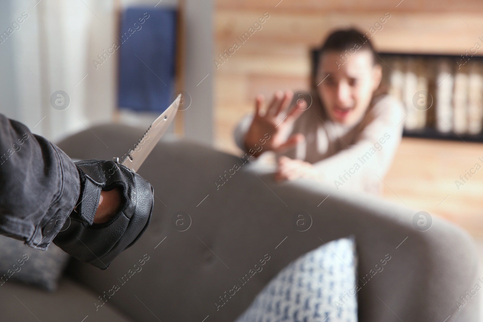 Photo of Man threatening victim with knife indoors, closeup. Dangerous criminal