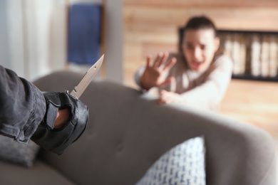 Man threatening victim with knife indoors, closeup. Dangerous criminal