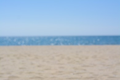 Sandy beach near sea on sunny day, blurred view