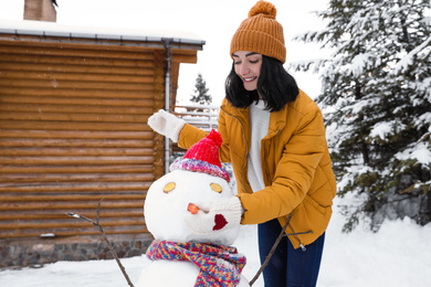 Photo of Happy woman making snowman outdoors. Winter vacation
