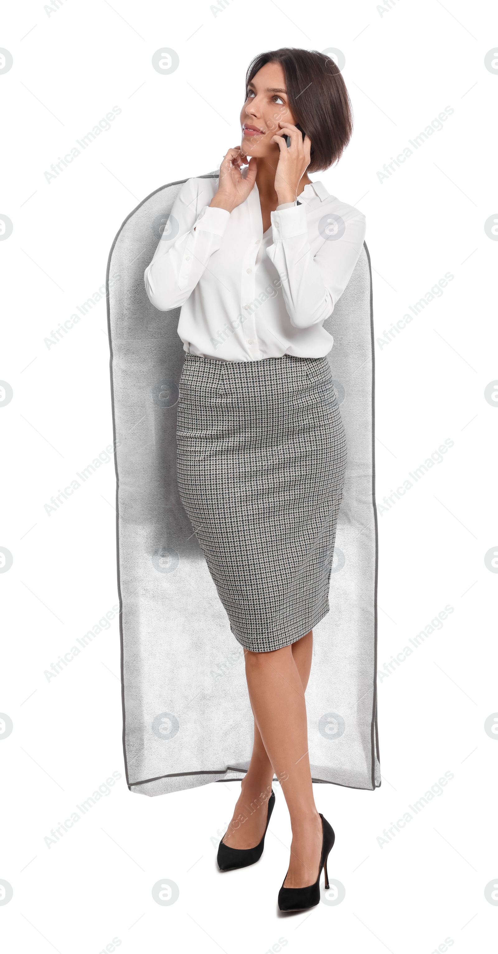 Photo of Woman holding garment cover with clothes while talking on phone, isolated on white. Dry-cleaning service