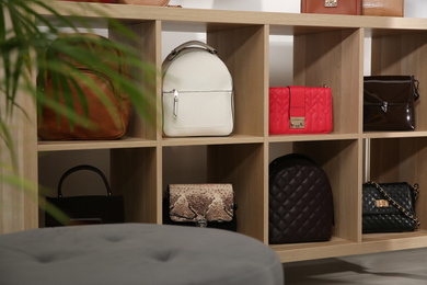 Photo of Collection of stylish woman's bags on wooden shelving unit