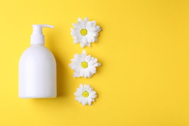 Photo of Bottle with body care cream and flowers on color background
