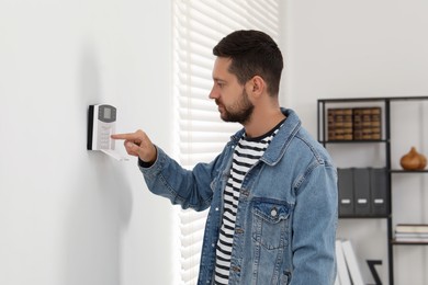 Photo of Man entering code on home security system indoors