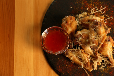 Photo of Tasty BBQ wings with red sauce served on table in cafe, top view