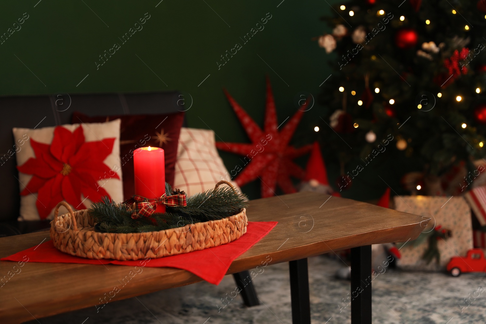 Photo of Wicker tray with red candle and fir branches on wooden table indoors, space for text. Christmas decor
