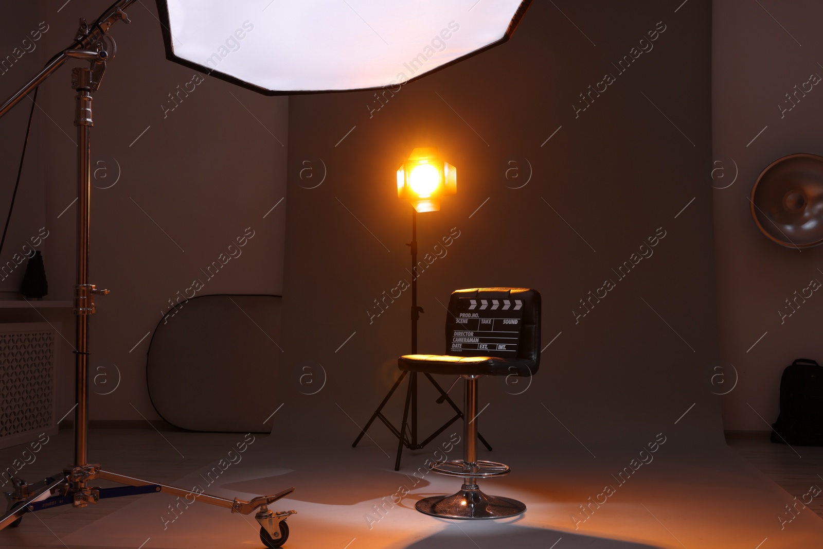 Photo of Casting call. Chair, clapperboard and different equipment in modern studio