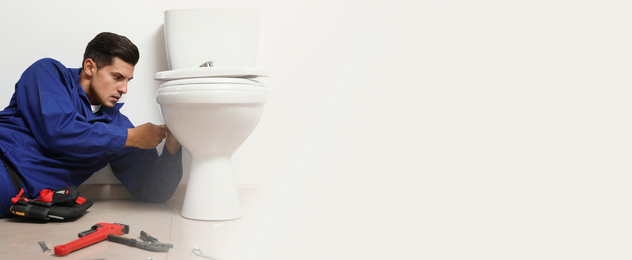 Professional plumber working with toilet bowl in bathroom, space for text. Banner design