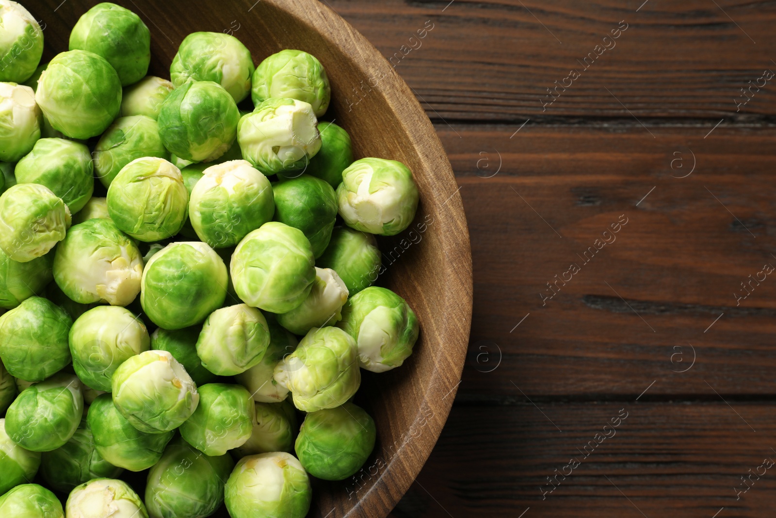 Photo of Bowl of fresh Brussels sprouts on wooden background, top view with space for text