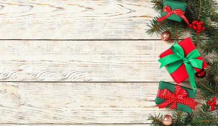 Photo of Gift boxes, Christmas balls and fir branches on white wooden background, flat lay. Space for text