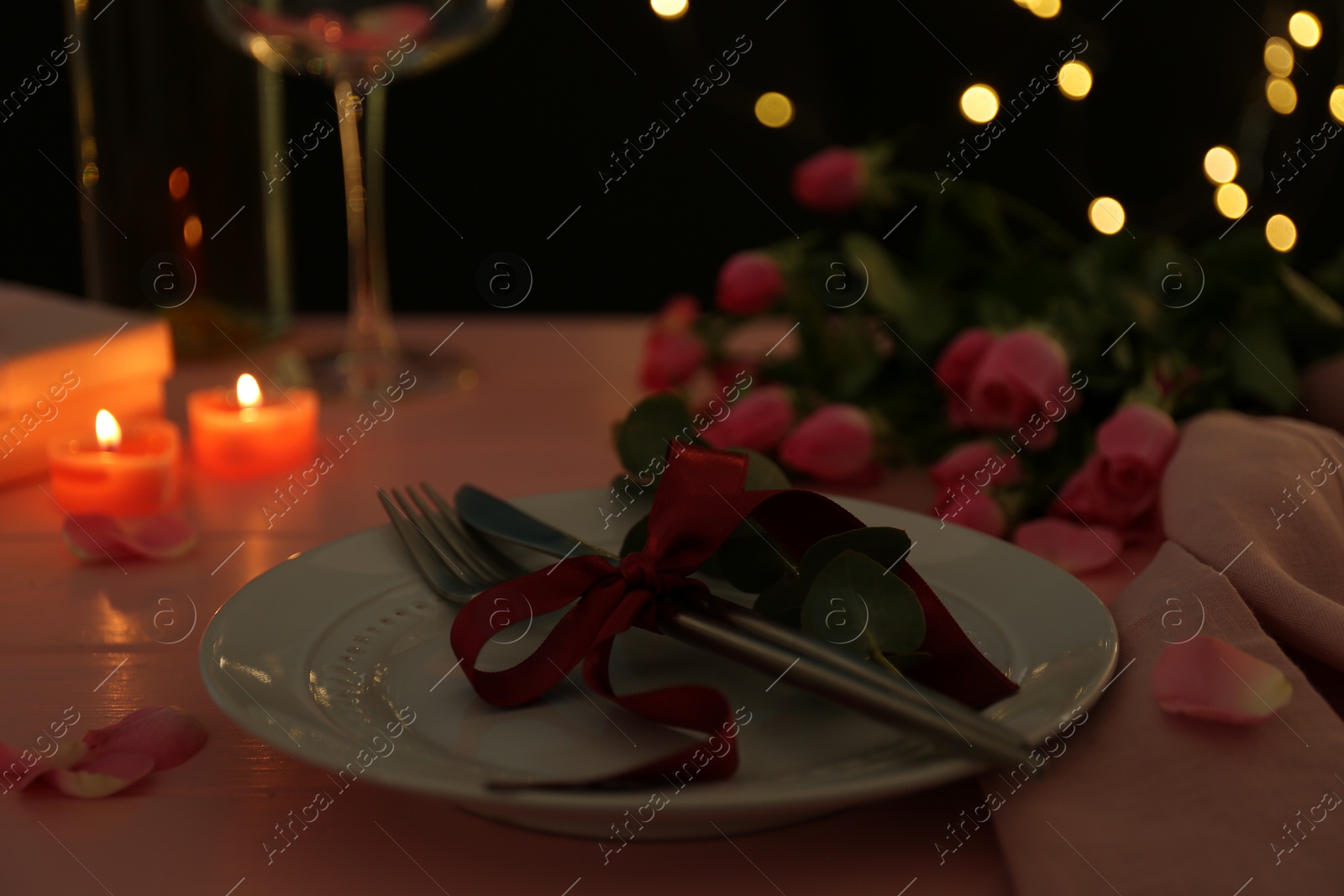 Photo of Place setting with roses and candles on pink wooden table, closeup. Romantic dinner