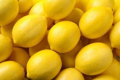 Photo of Ripe lemon fruits as background, top view