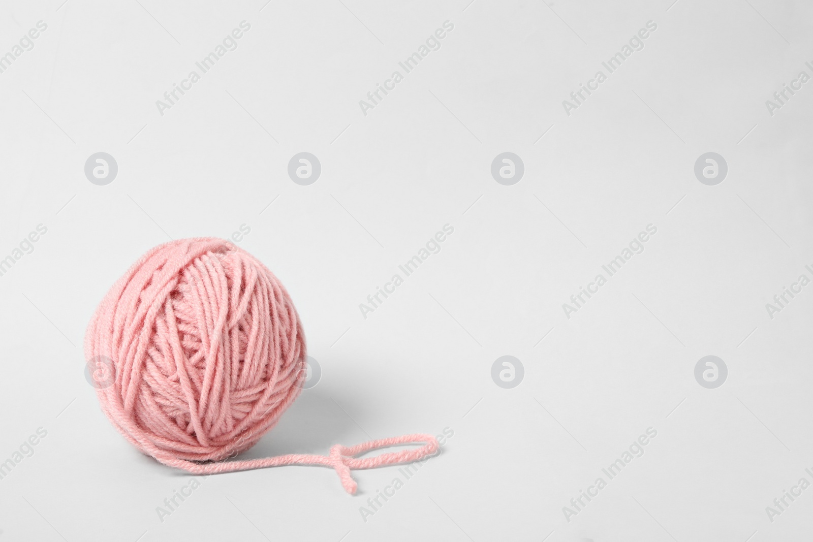 Photo of Soft pink woolen yarn on white background