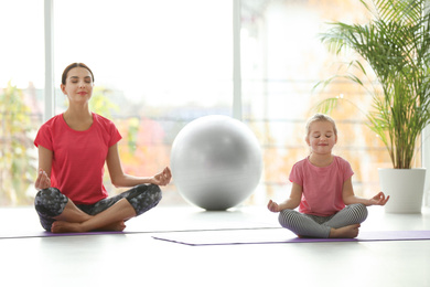 Photo of Woman and daughter meditating together at home. Fitness lifestyle