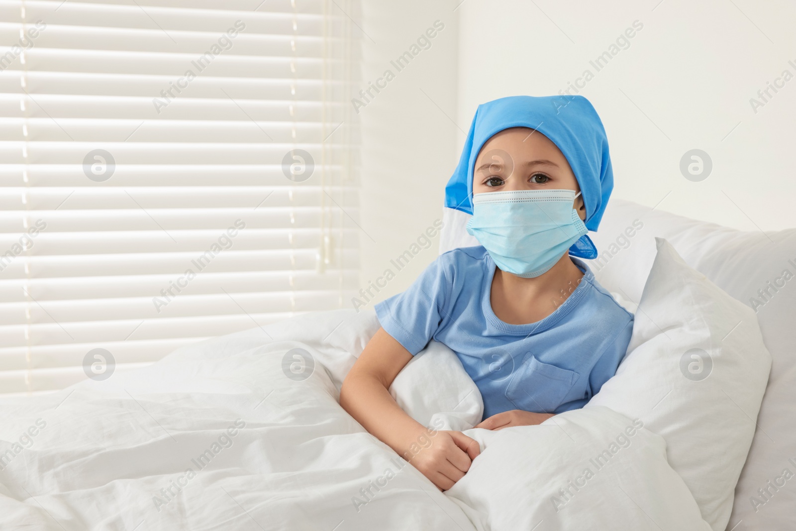 Photo of Childhood cancer. Girl wearing medical face mask in hospital