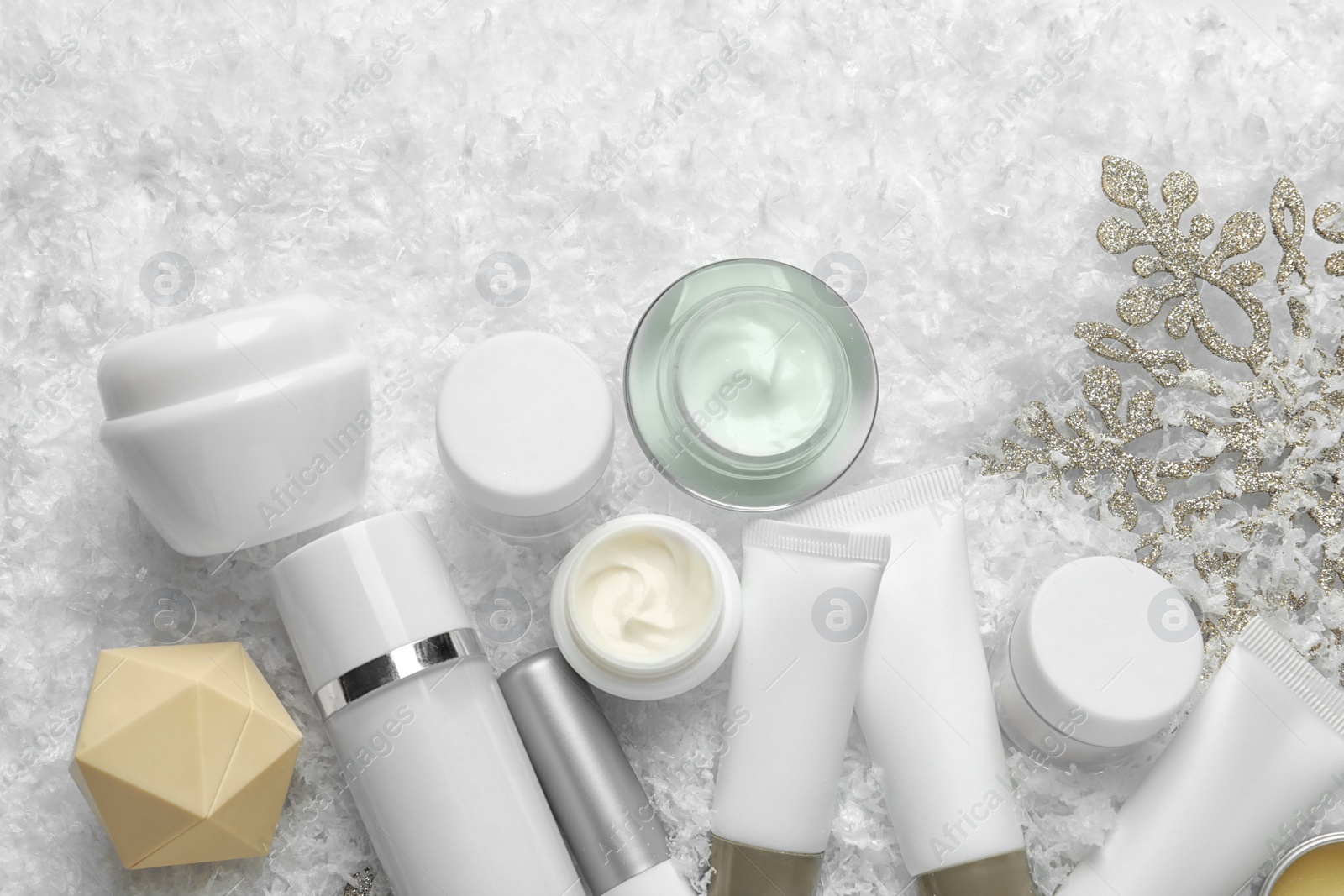 Photo of Set of cosmetic products on decorative snow, flat lay. Winter care