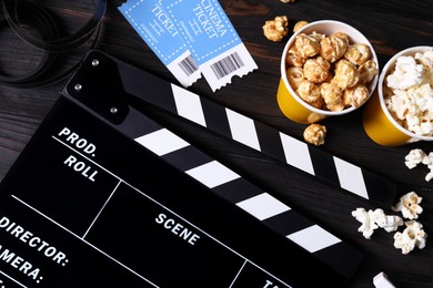 Photo of Clapperboard, movie tickets, popcorn and film reel on wooden table, flat lay