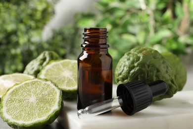 Photo of Glass bottle of bergamot essential oil and dropper on table
