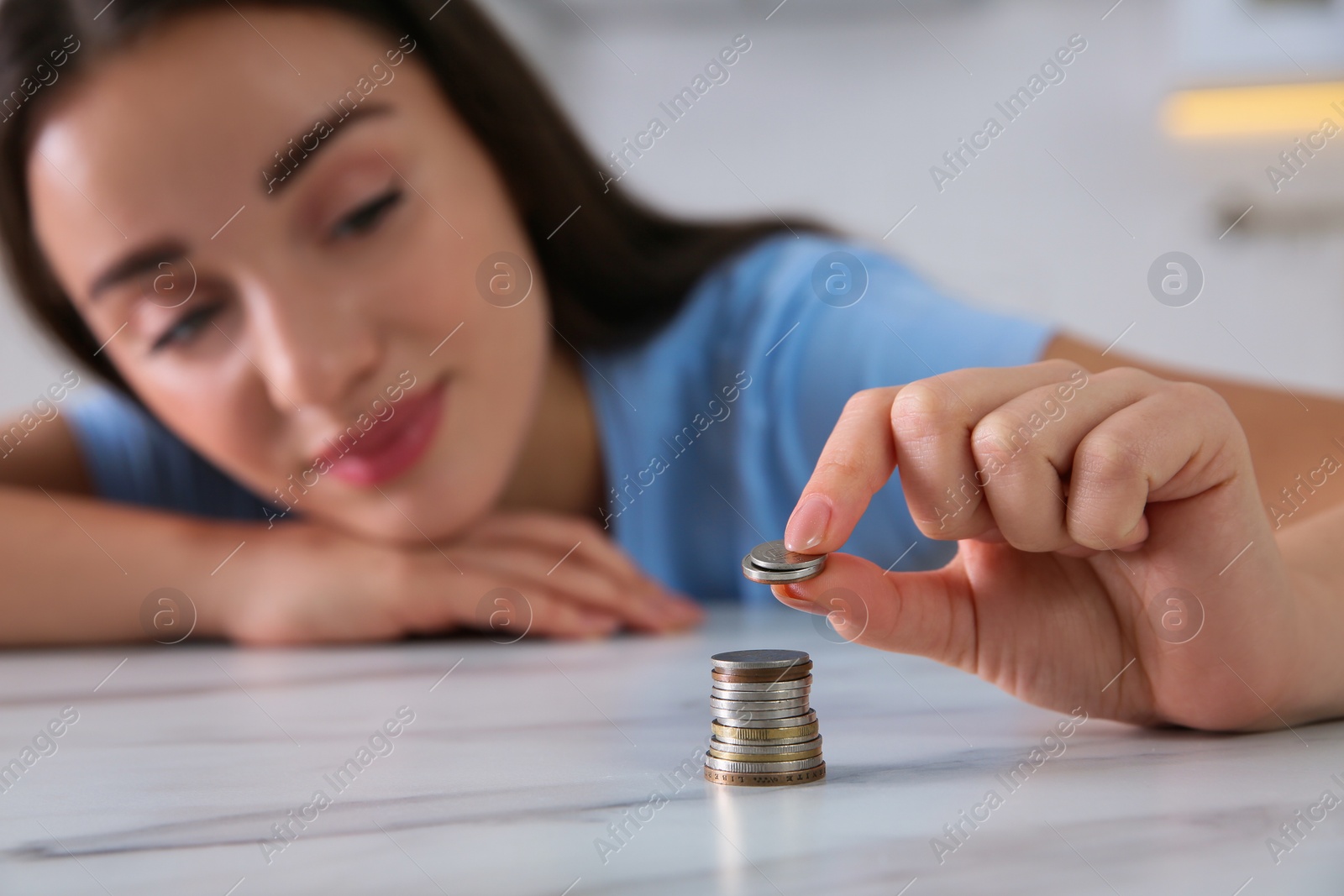 Photo of Young woman stacking coins at table, focus on hand. Money savings